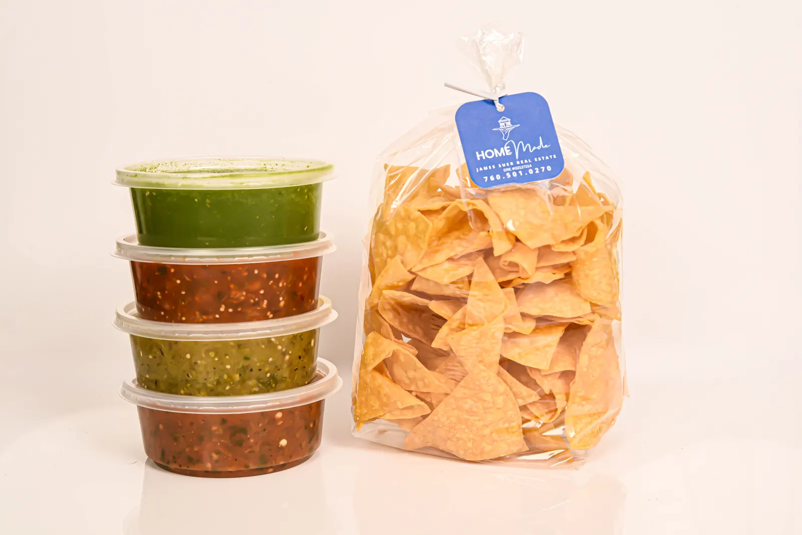 A stack of HOMEmade salsa tubs next to a big bag of chips